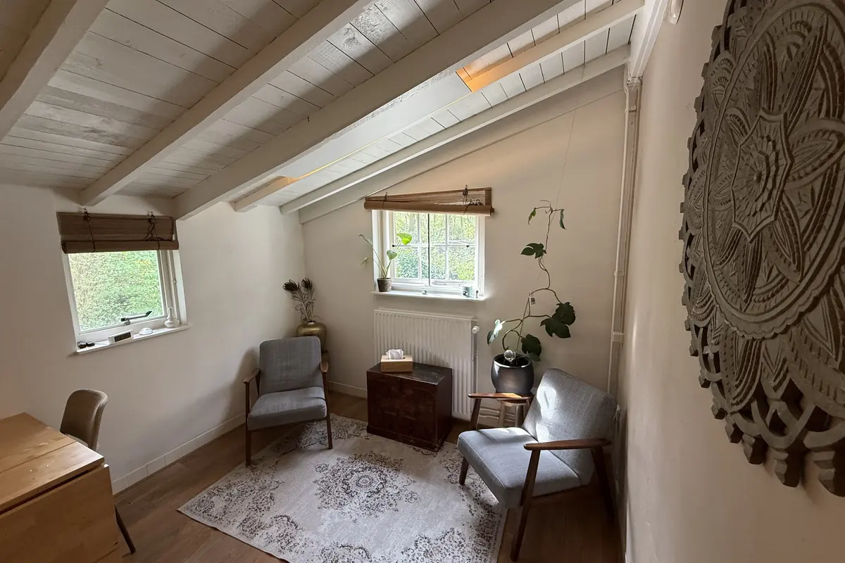 Therapy studio with two armchairs, beamed white ceiling and garden windows